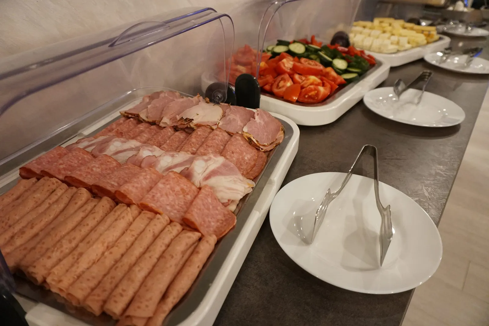 A platter of cold cuts, tomatoes and cucumbers on the buffet