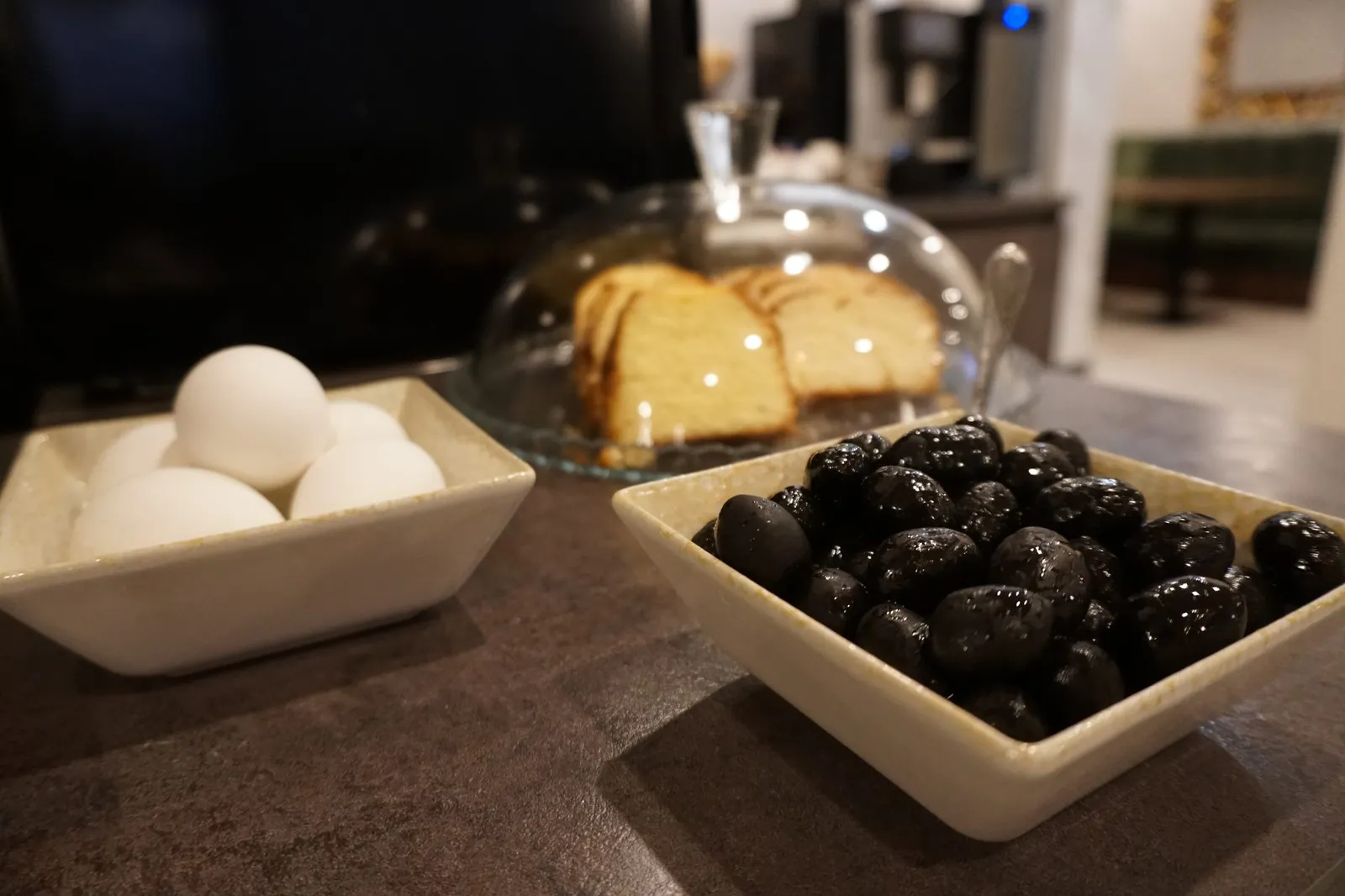 Boiled eggs, olives and sponge cake under a glass dome
