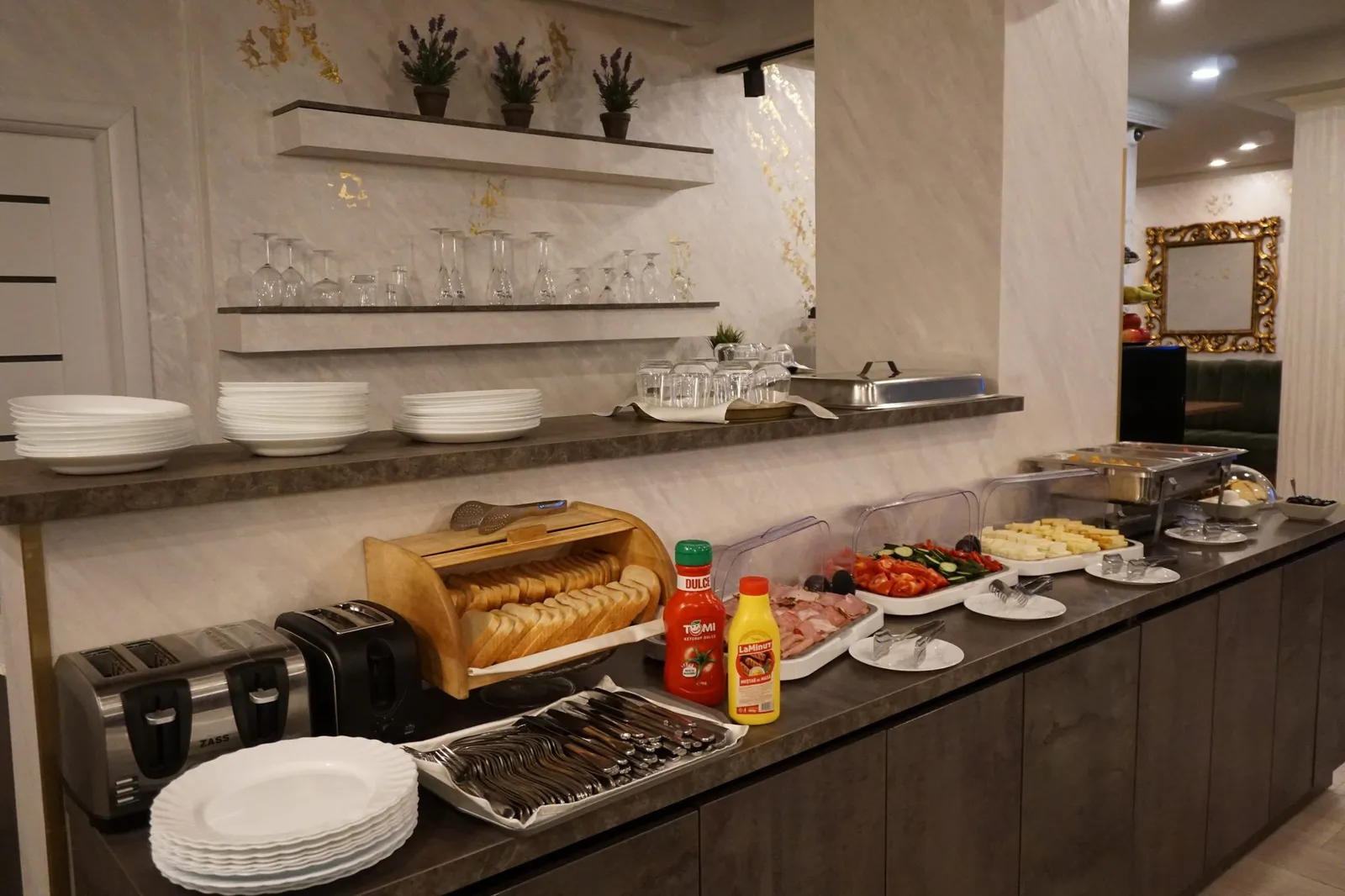 The breakfast buffet, with bread, cold cuts, vegetables and plates