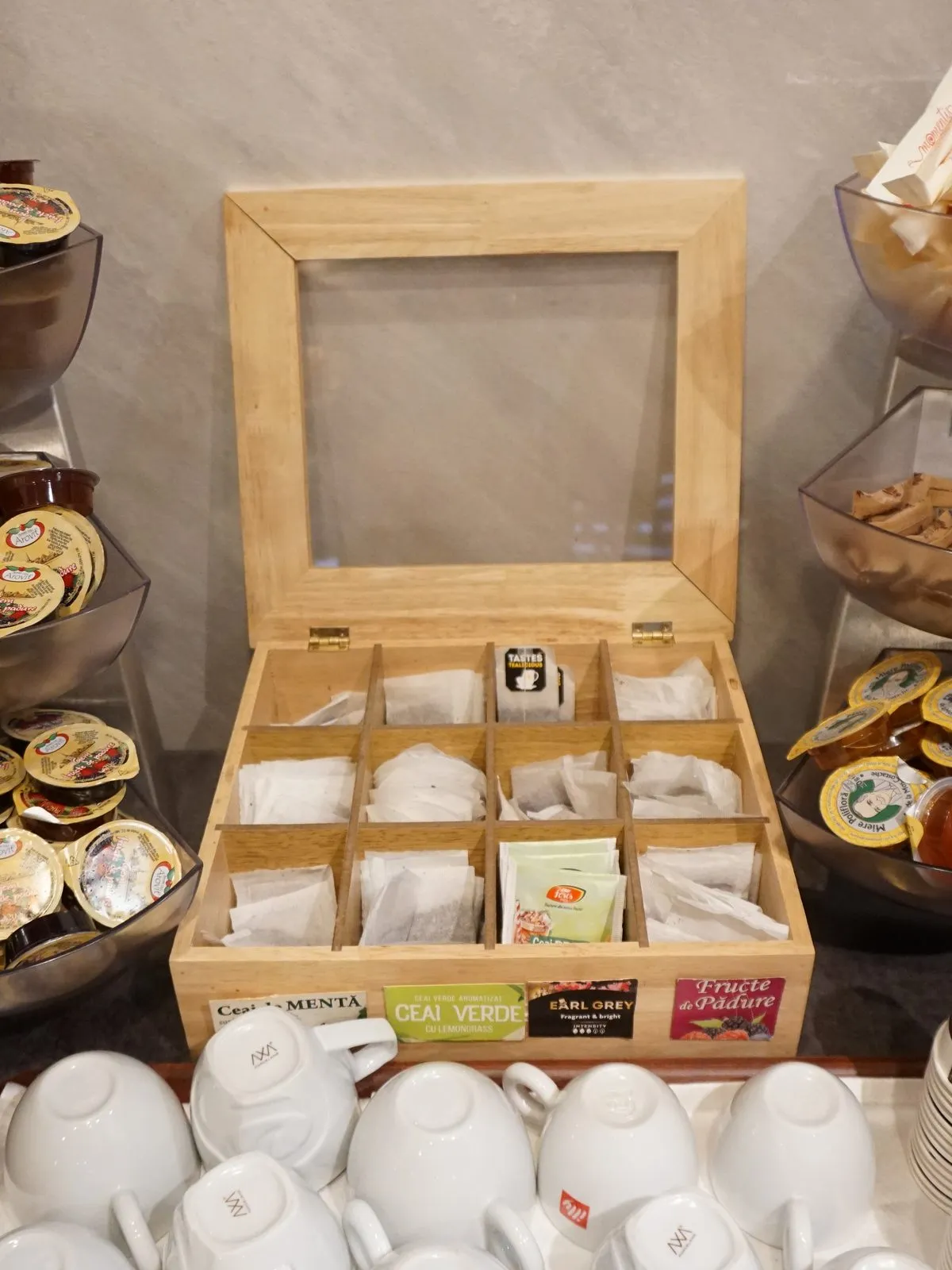 Teas, jams and honey in single portions, next to cups