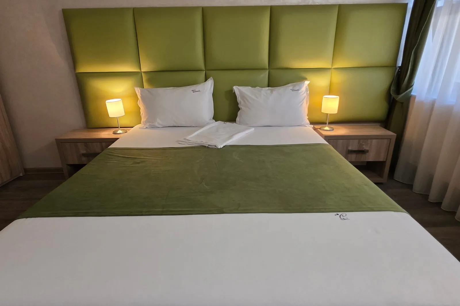 The triple room's double bed, with a green tufted headboard